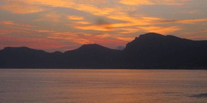 Sonnenuntergang über der Bucht mit Blick auf die Berge