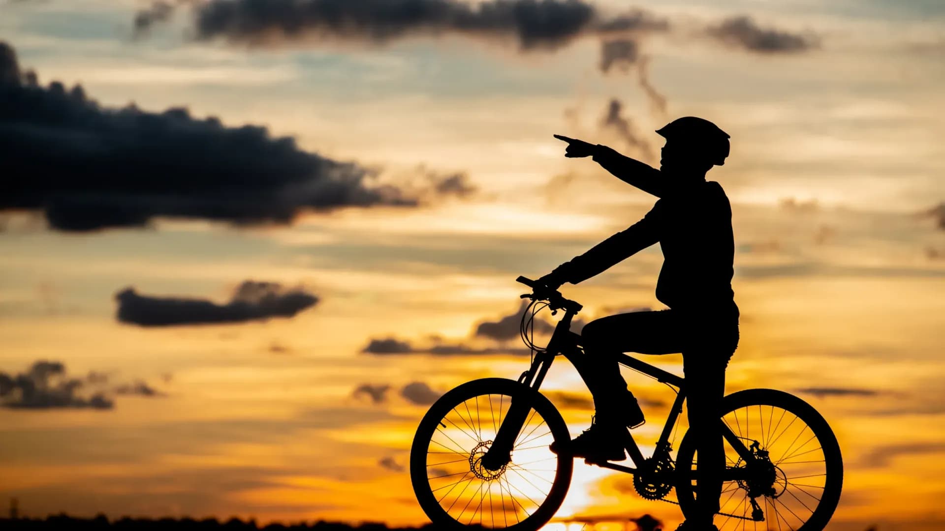 Radfahrer zeigt in den Sonnenuntergang, Silhouette am Abend auf Mallorca